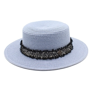Detail of light blue straw flat top hat with woven band and gold metal M logo charm