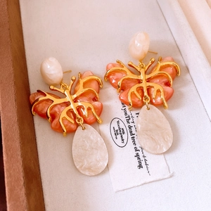 Detail of butterfly drop earrings with coral resin and white teardrop pendant