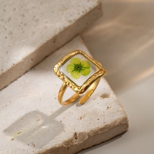 Macro detail of a vintage gold ring with real green flower preserved in square resin