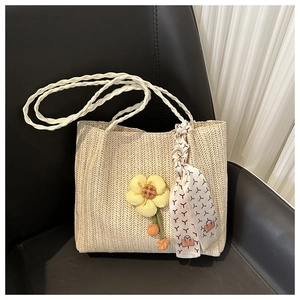 Close-up of woven straw bucket bag featuring a yellow daisy charm and decorative scarf
