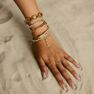Bracelet bague serpent en acier titane avec finition or et strass sur le sable