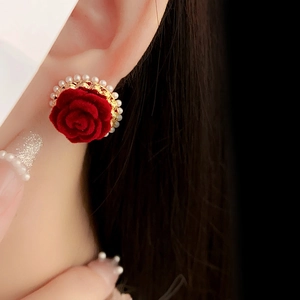 Gros plan de boucles d'oreilles fleurs rouges avec base dorée et accents de perles