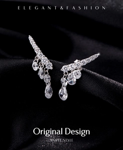 Detailed view of silver wing earrings with sparkling stones on black silk fabric