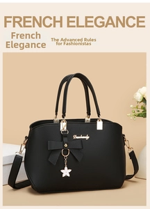 Detail of black lychee textured tote bag with metal star pendant and bow decoration