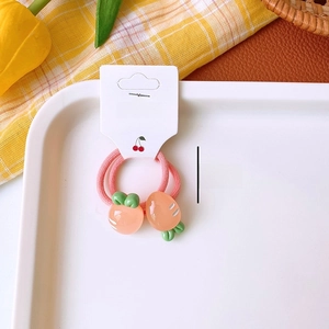 Detail of two peach and carrot elastic hair ties for girls on a white display card