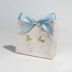 Detail of marble pattern gift bag with blue satin ribbon and gold Thank You foil text