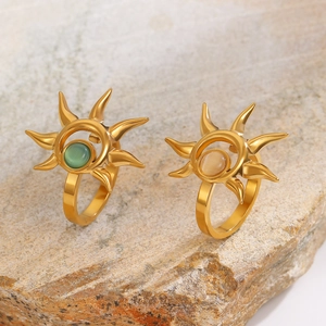Detailed close-up of sunflower gold rings with green and pink gemstones on natural rock