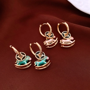 Close-up of 18K gold plated rocking horse earrings in white and teal enamel