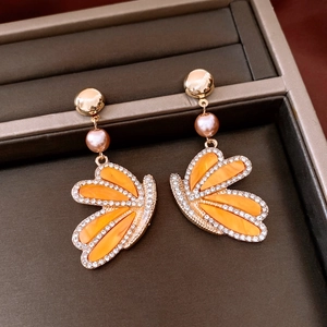 Close-up of vintage gold butterfly earrings with amber resin wings and purple pearls