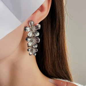 Close-up of vintage silver flower tassel earrings on a model with metallic texture
