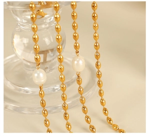 Macro view of gold-plated metal bead chain and pearls hanging on a glass container