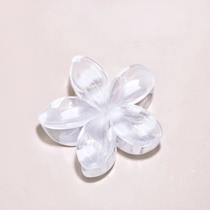 Macro detail of creamy white plumeria flower hair claw clip with gold metal spring