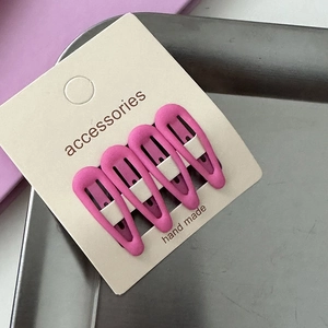 Detailed view of four matte pink teardrop hair clips on an accessories display card