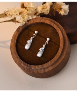 Macro detail of teardrop S925 silver earrings with brushed texture on a jewelry box
