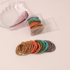 Close-up of colorful high-elastic spiral hair ties in a clear acrylic storage box