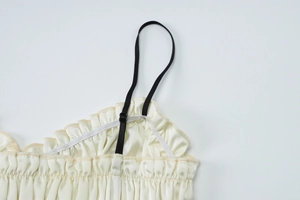 Detail of beige chiffon camisole with black adjustable straps and ruffle neckline