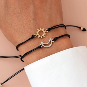 Close-up of adjustable black woven sun and moon charms friendship bracelets on wrist