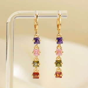 Long gold drop earrings with multi-colored square zircons on an acrylic display stand