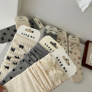 Ballet style cream lace socks with bows and floral patterns in a layered pile design