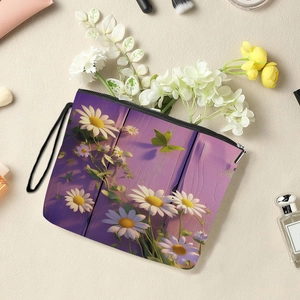 Floral print canvas makeup bag with zipper closure and wrist strap on a sand texture background