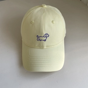 Detail of cute purple dachshund embroidery on a cream yellow cotton baseball cap