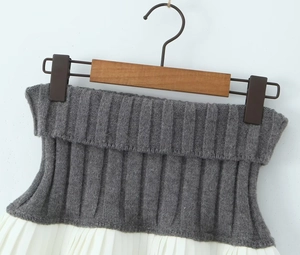 Close-up of contrast knit high waistband and white pleated layered short skirt details