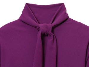 Détail de la robe en crêpe violette montrant le col à nœud et la texture du tissu gaufré