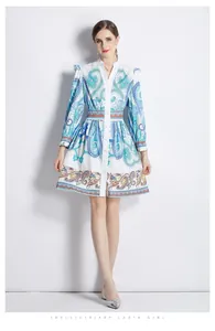 Détail du col en V avec boutons et imprimé cachemire bleu sur une robe blanche