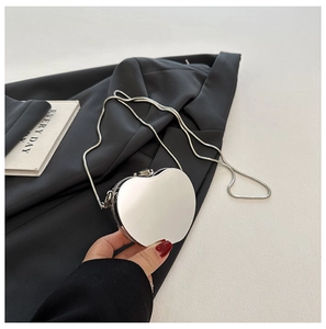 Detail of silver heart-shaped acrylic mini clutch bag held over black blazer
