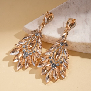 Macro shot of champagne gold teardrop earrings with crystals on natural stone background