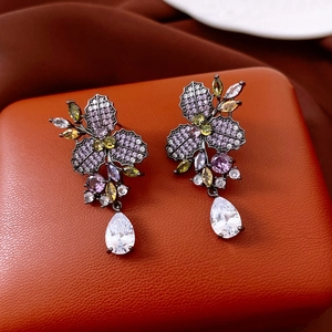 Dettaglio macro di orecchini vintage con zirconi viola a fiore e pendenti a goccia