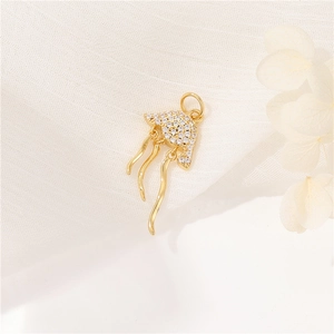 Macro shot of 14K gold jellyfish pendant with sparkling crystals on white fabric