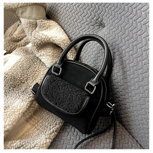 Detail of black wool fabric handbag featuring plush faux fur flap and smooth top handle