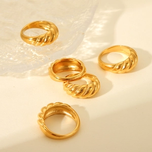 Close-up of gold croissant dome rings on a glass plate with soft lighting