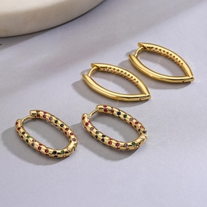 Pendientes de aro ovales chapados en oro con circonitas de colores sobre fondo gris