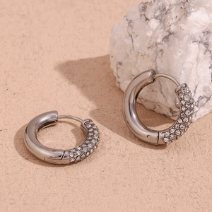 Dettaglio ravvicinato di orecchini a cerchio in acciaio argento con intarsi in zircone