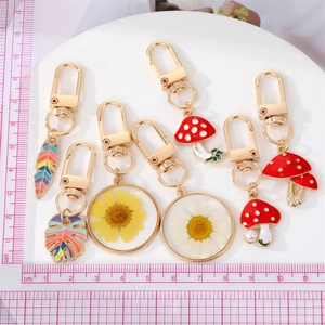 Detailed set of gold alloy keychains with colorful enamel mushrooms and dried flower resin