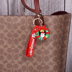 Christmas wreath keychain with Santa and red strap on a brown leather handbag
