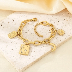 Detail of a gold-tone chunky chain bracelet with sparkling celestial charms on stone