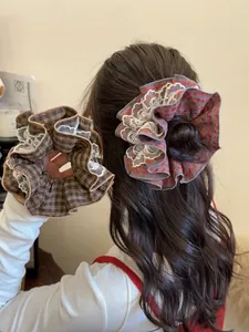 Close-up of vintage red plaid scrunchie with delicate white floral lace trim detailing