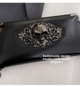 Detail of gothic skull pattern and metal corners on shiny black leather wallet
