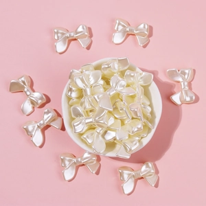 Close-up of cream resin pearl bow beads in a ceramic bowl for DIY jewelry making