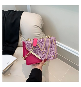 Detail view of purple marble pattern shoulder bag with golden chain and pink flap