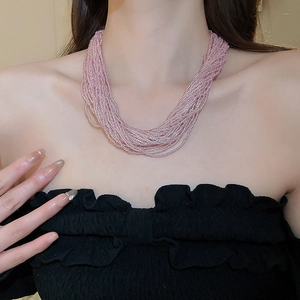 Close-up of pink multi-layered beaded lace necklace on model with high texture