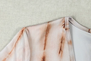 Detail of V-neck stitching and tie-dye print on loose-fitting casual long-sleeve dress