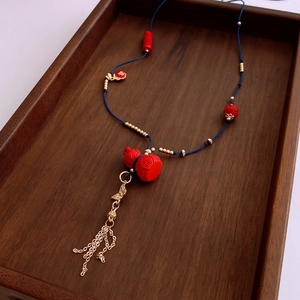 Detail of red cinnabar gourd pendant with gold tassels on a woven ethnic necklace
