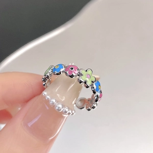 Detail of adjustable silver ring featuring colorful enamel floral motifs on finger