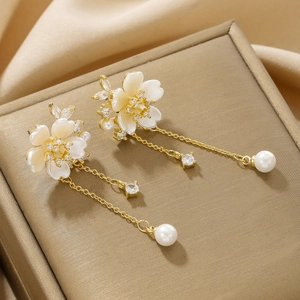 Macro detail of 18K gold flower earrings with white petals, crystals and pearl drops