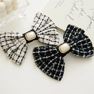 Detail of tweed bow hair clips with pearls and rhinestones on a black and white fabric