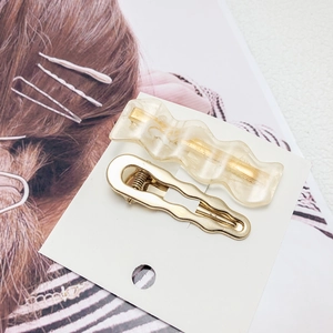 Beige resin and gold wavy hair clip set on white card with a stylish background